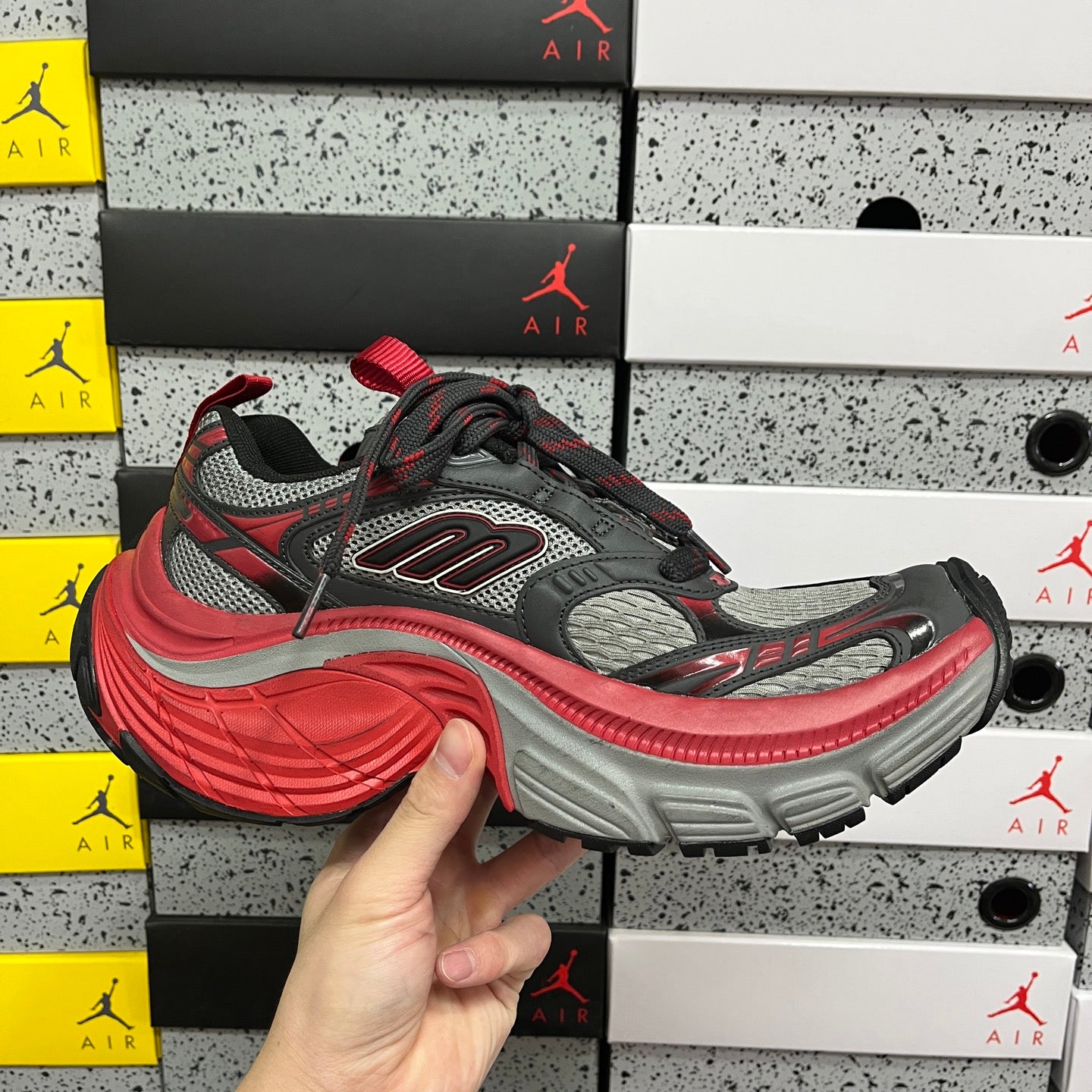 Chunky low-top sneaker side view: gray sole with red edging and black laces