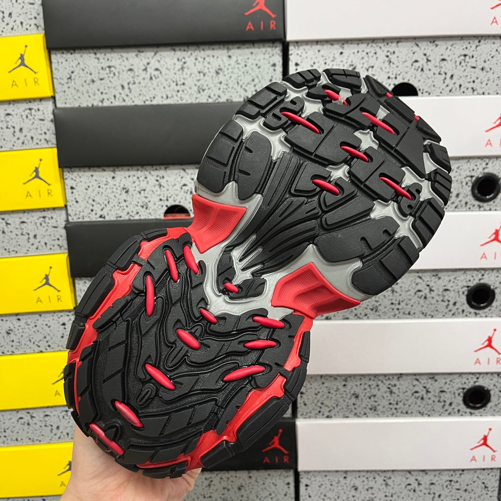 Sneaker outsole with rugged black tread and red accent shapes