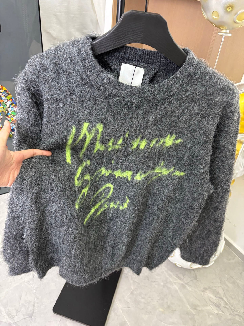 Dark gray fuzzy sweater on hanger with neon green graphic print, long sleeves