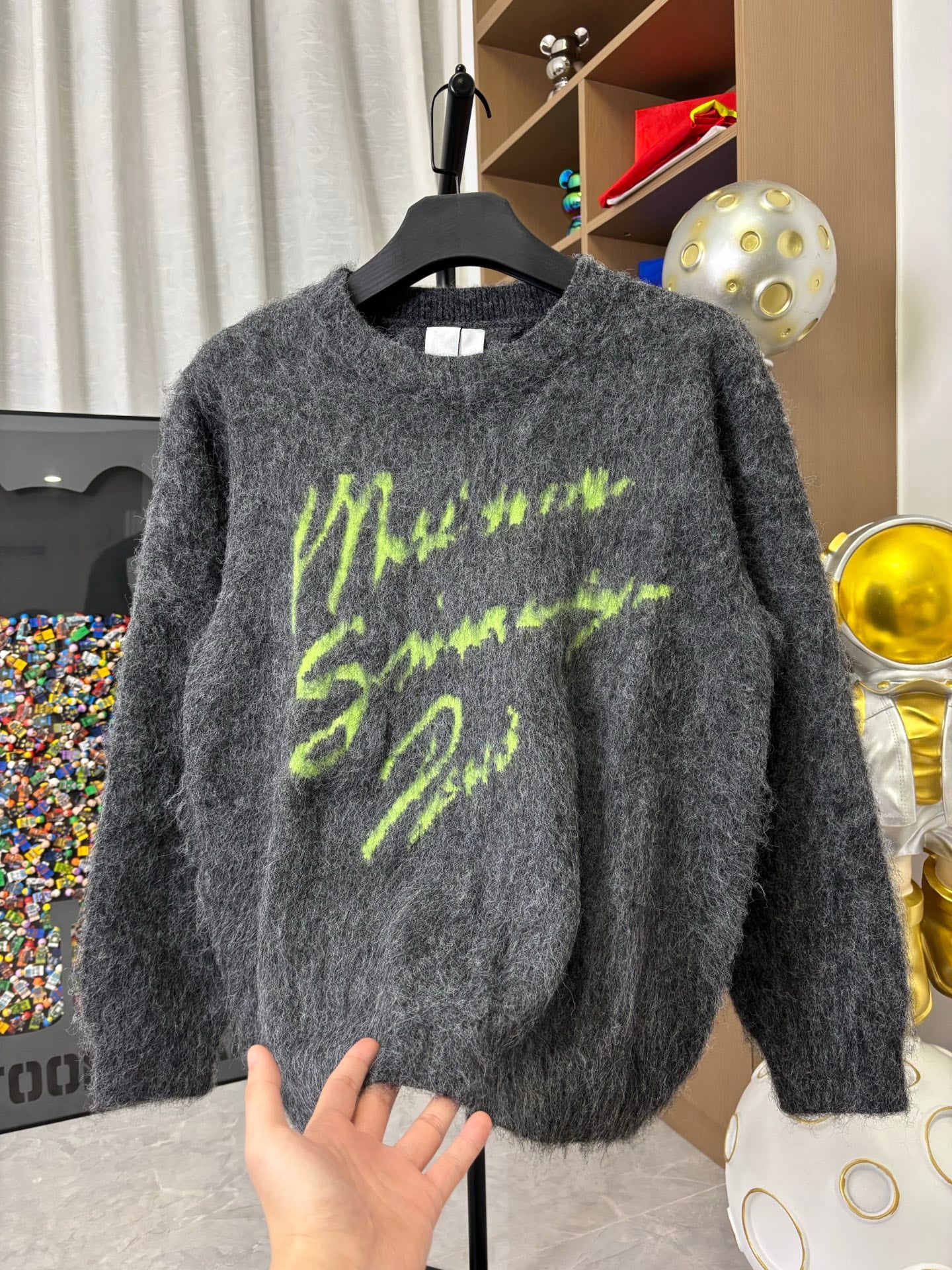 Dark gray fuzzy crewneck sweater with neon green graphic print, long sleeves