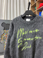 Dark gray fuzzy crewneck sweater with neon green graphic print, close-up