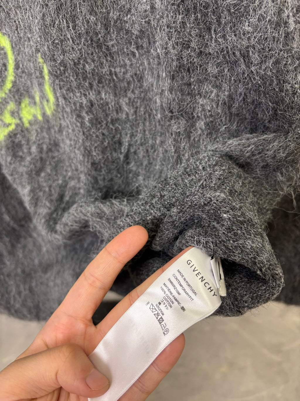 Dark gray fuzzy sweater fabric with GIVENCHY label and care tag, close-up