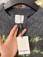Dark gray sweater neckline with white label and GIVENCHY tag, close-up
