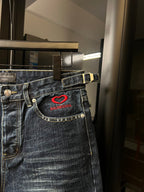 Balenciaga denim shorts waist detail with red heart logo patch and gold-trim stitching