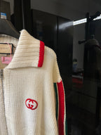 Gucci cream knit sweater showing red shoulder stripe and GG logo on sleeve