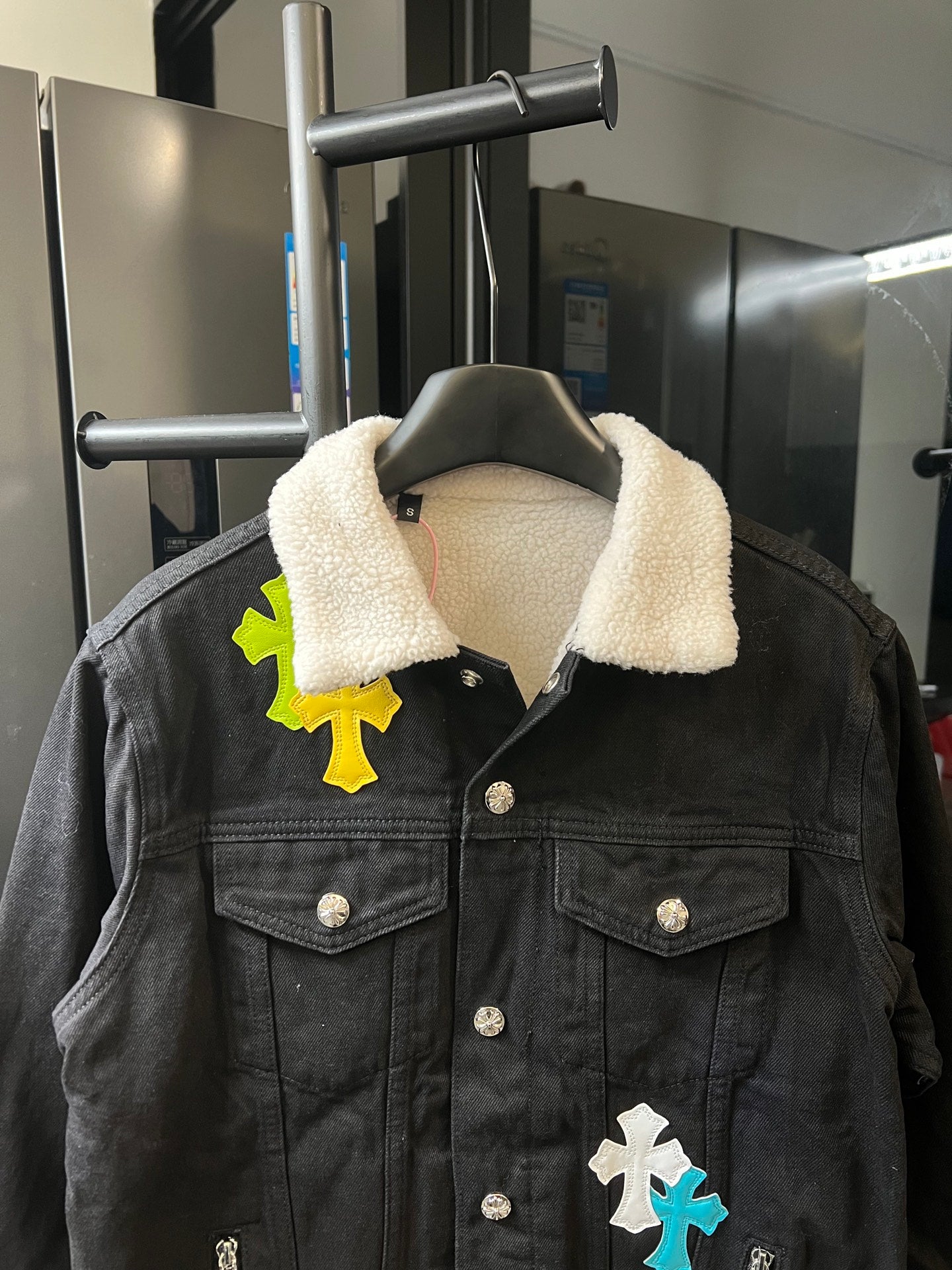Black denim jacket with sherpa collar, button front, cross patches on chest