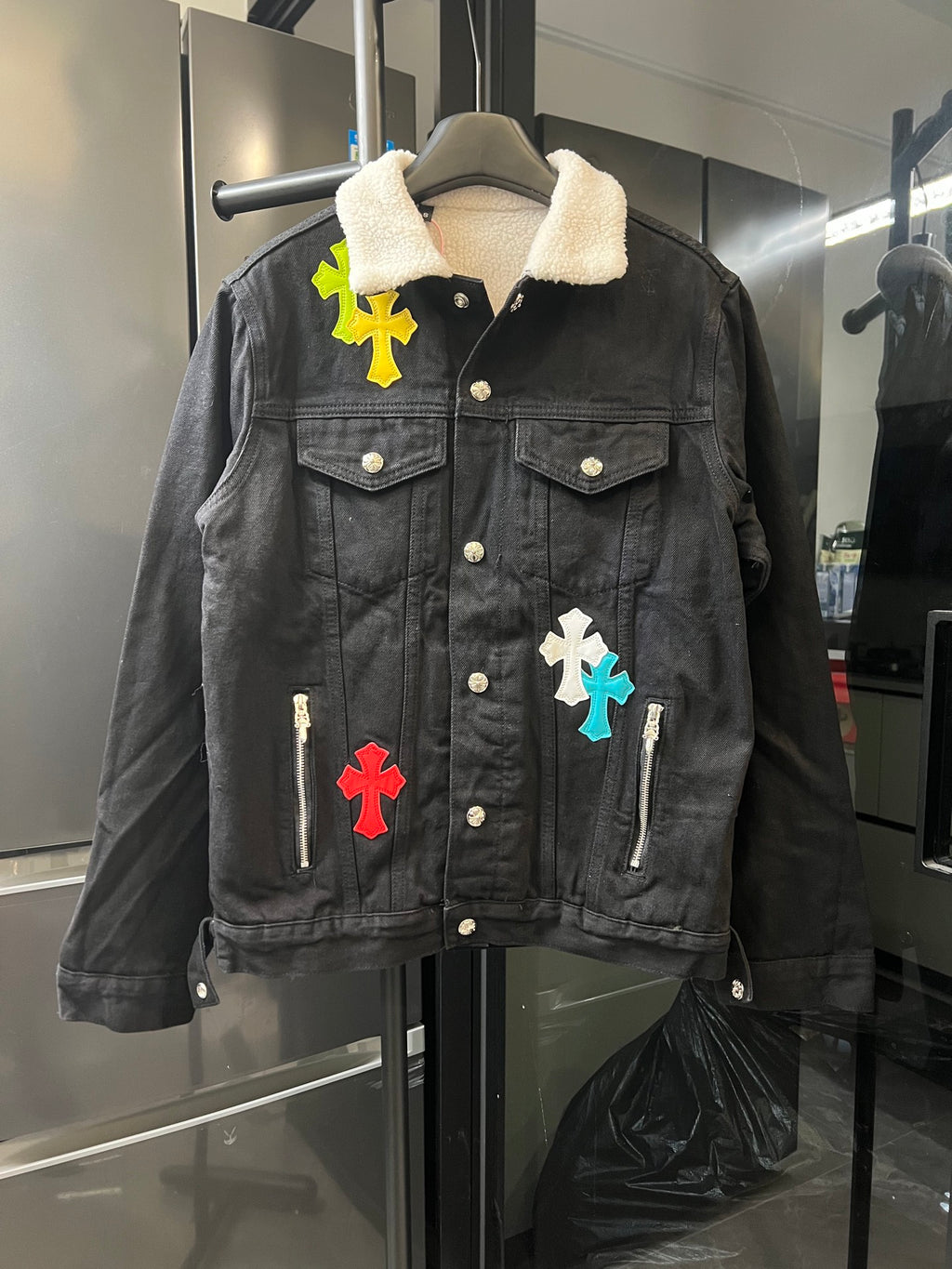 Black denim jacket with sherpa collar and colorful cross patches, button front