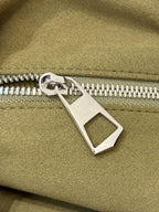 Silver-tone zipper pull on olive green leather bag with engraved bar