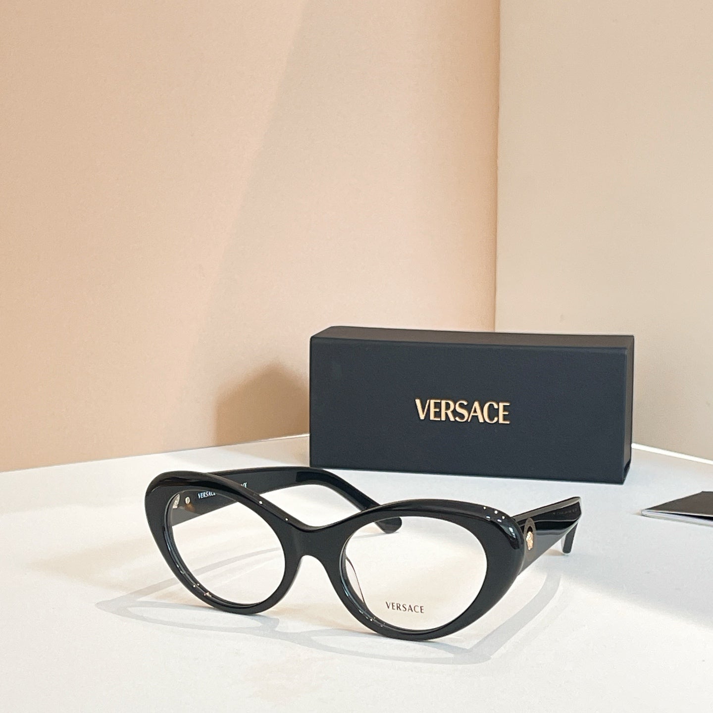 Round eyeglasses with dark frames and clear lenses, black temples with logo details