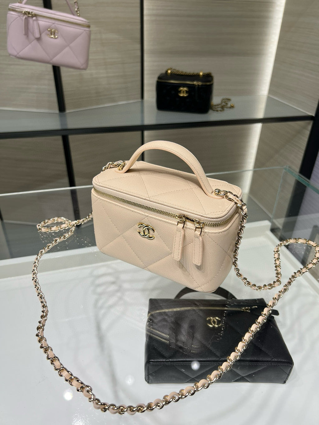 Chanel quilted handbag in light beige with top handle, zip, and chain strap.