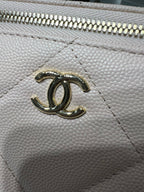 Chanel bag hardware close-up with CC emblem on textured light leather.