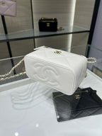 White quilted mini handbag with CC emblem, flap front, and gold chain strap.