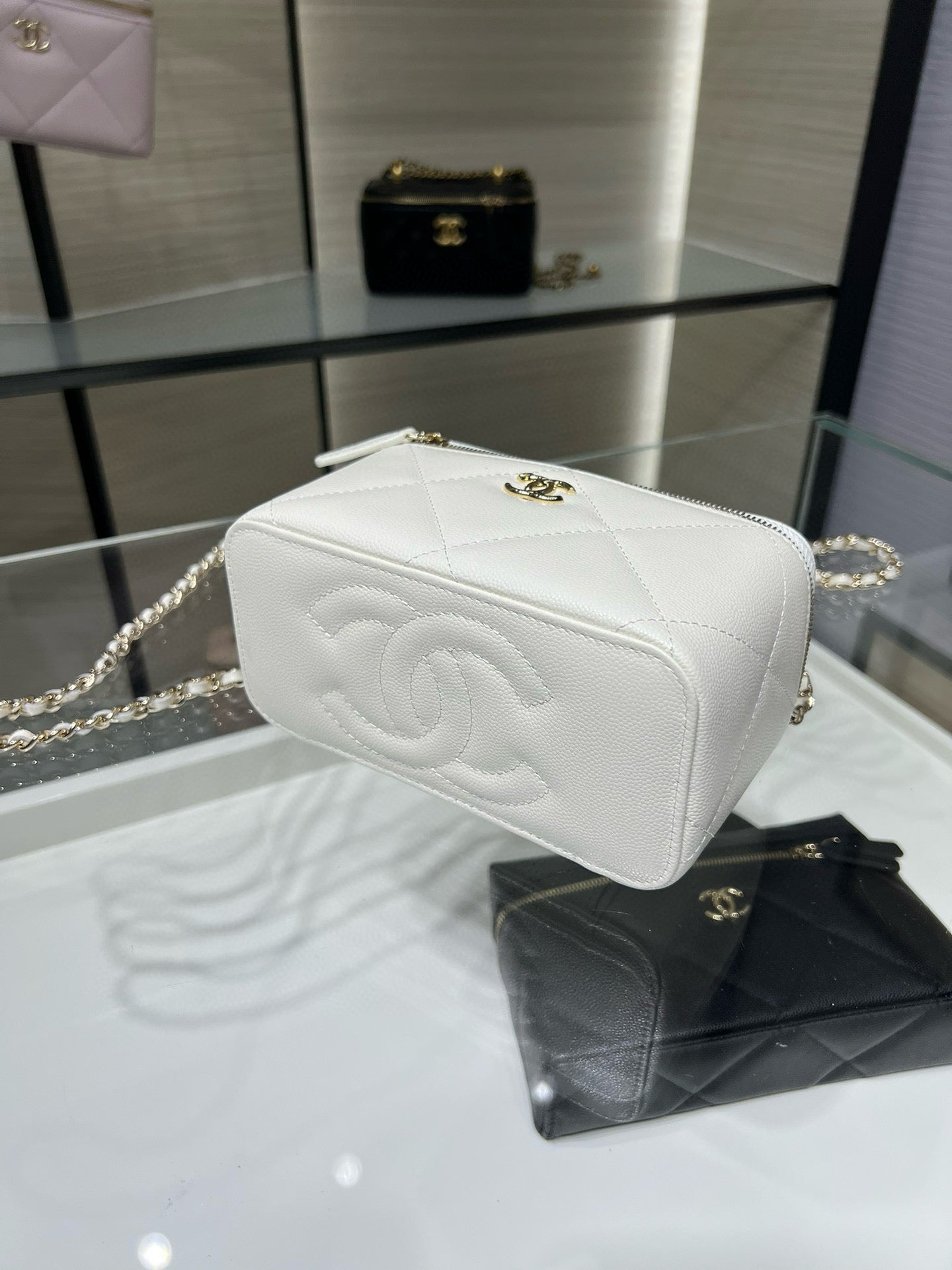 White quilted mini handbag with CC emblem, flap front, and gold chain strap.