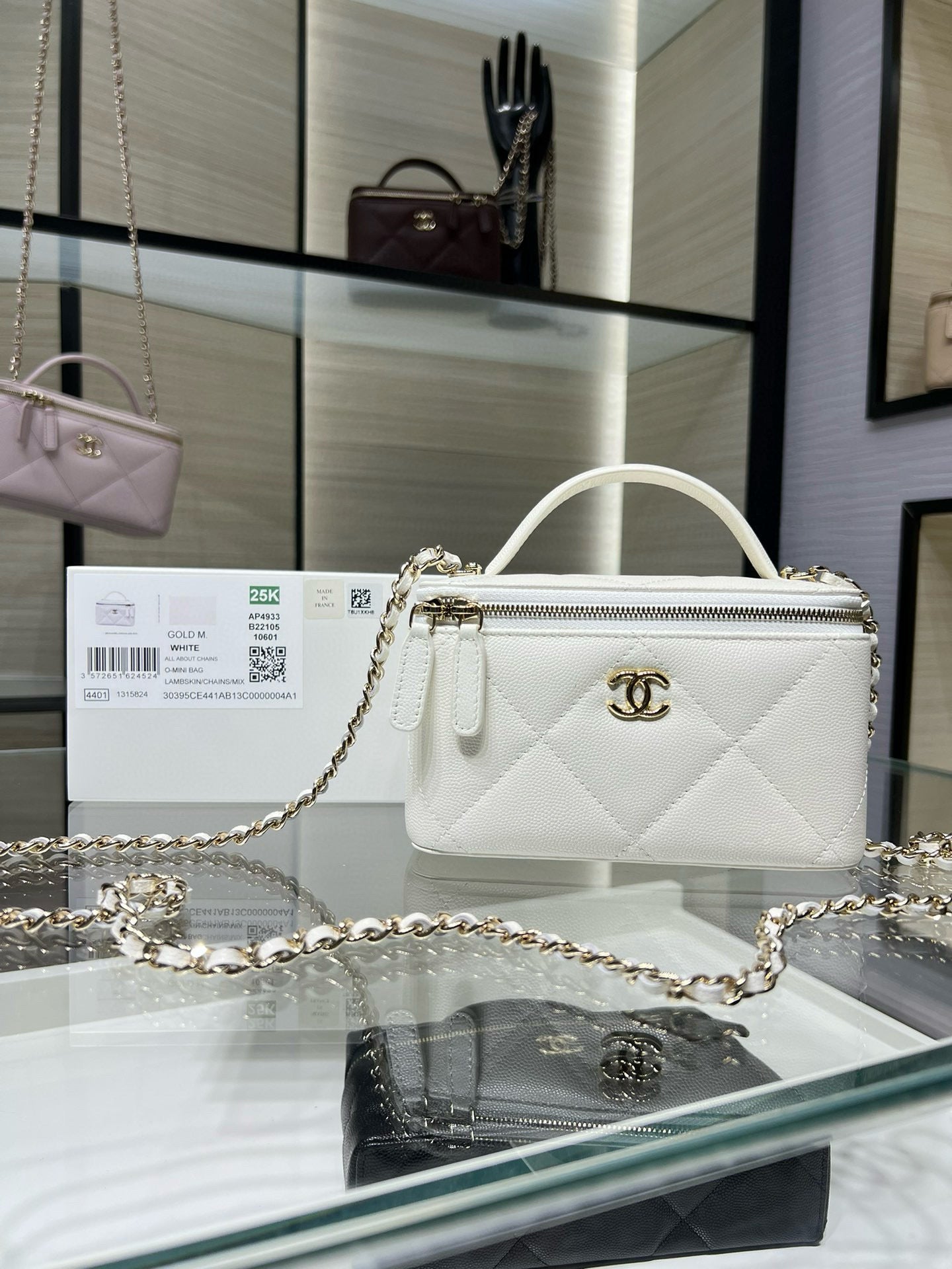White quilted handbag with top handle, gold chain strap, and CC logo front.