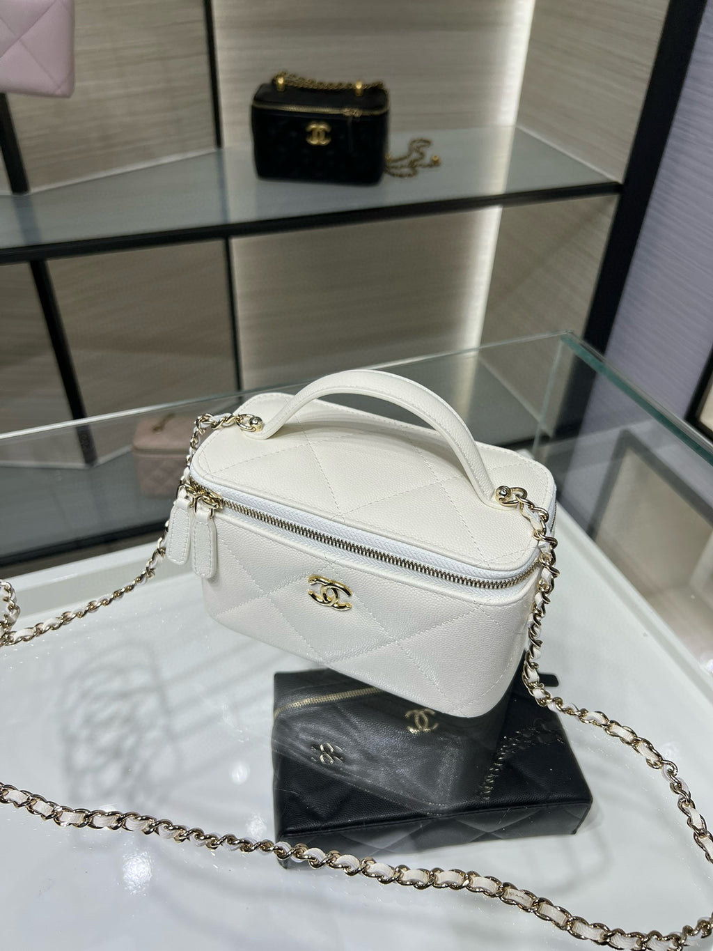 White quilted crossbody handbag with arched zipper top and gold chain strap hardware.