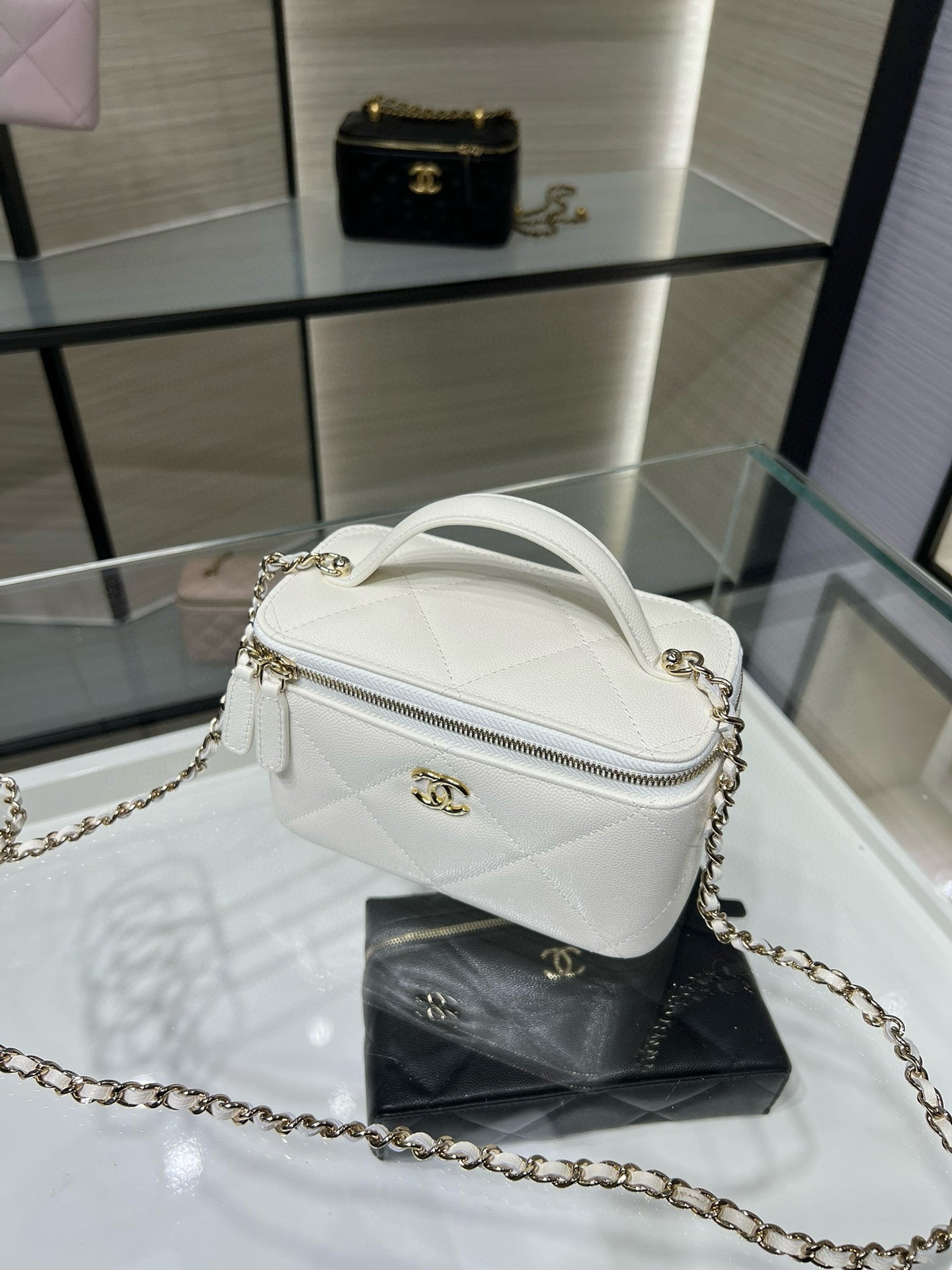 White quilted crossbody handbag with arched zipper top and gold chain strap hardware.