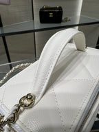 Close-up of white leather handbag top handle with gold chain strap connector.