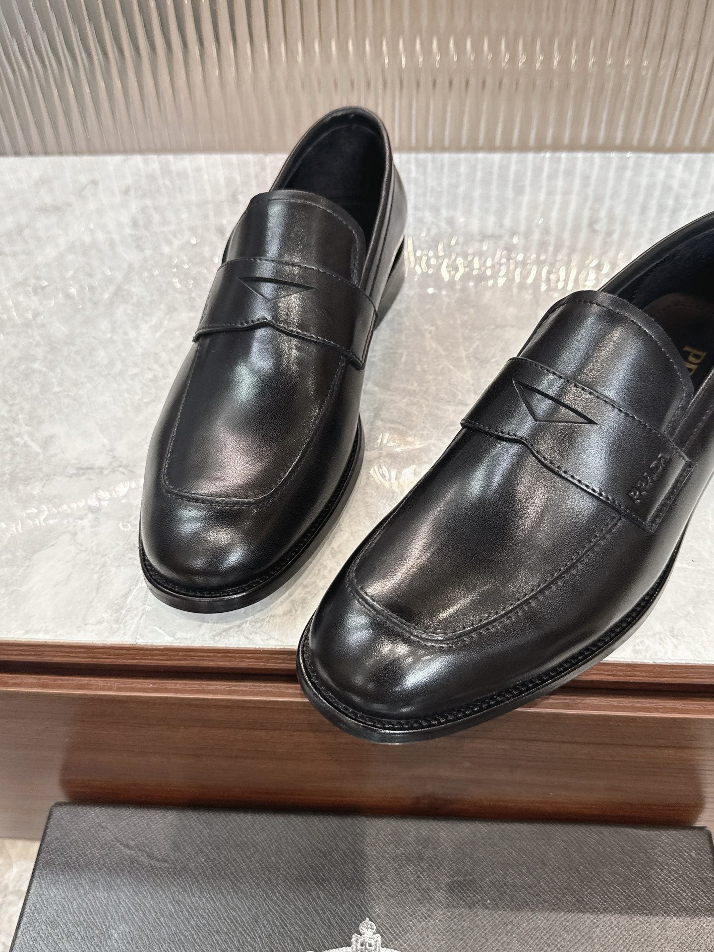 Black leather slip-on loafers, close side view with stitched seam across vamp