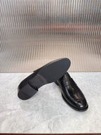 Black leather loafer with flat sole, side angle showing heel and toe