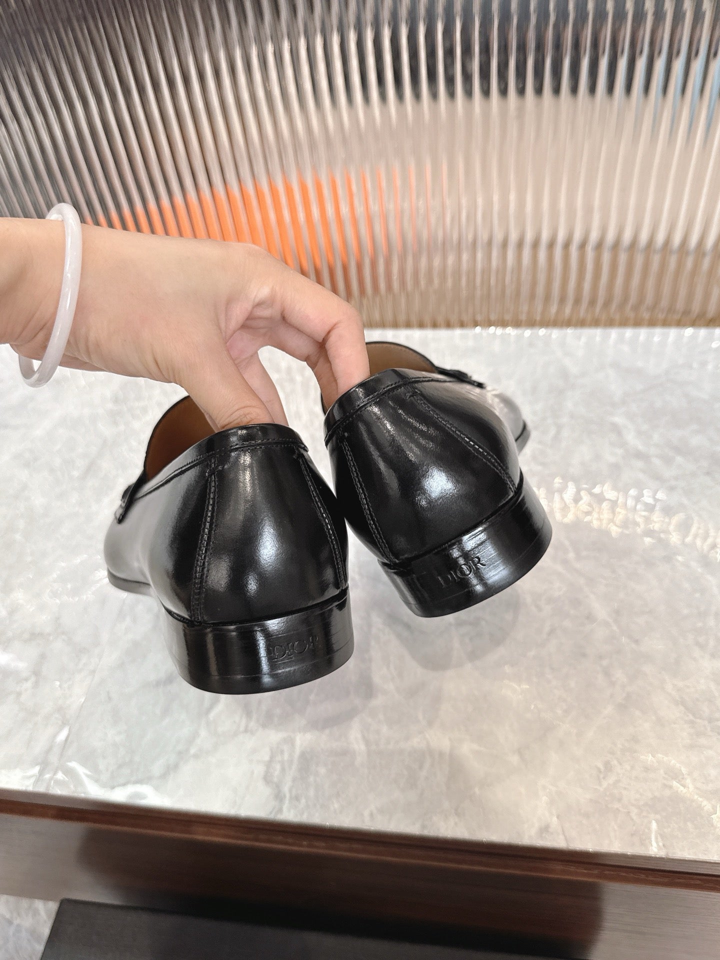 Black leather unisex loafers, heel and back view held in hand.
