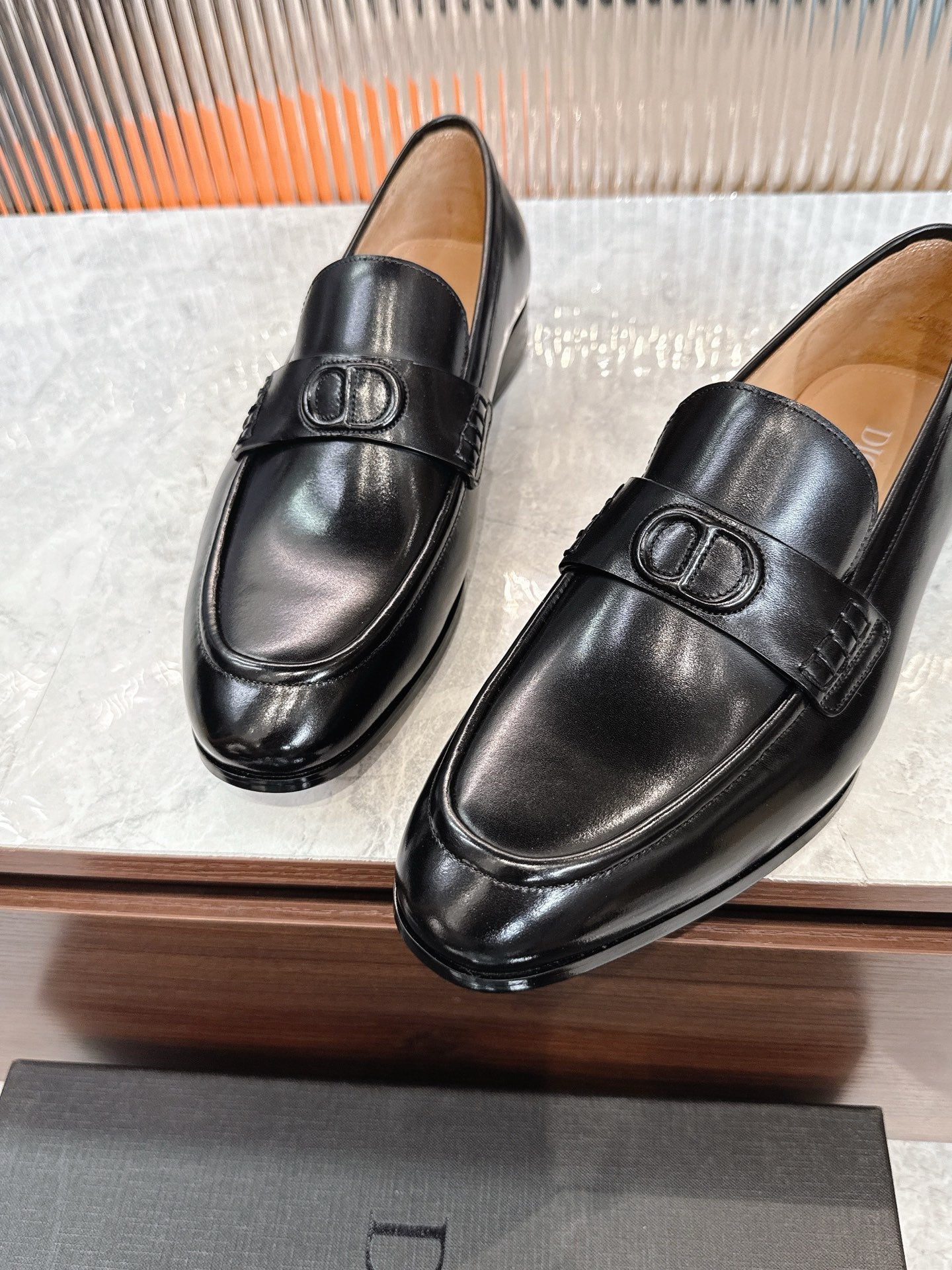 Black leather unisex loafers with embossed buckle ornament on vamp.