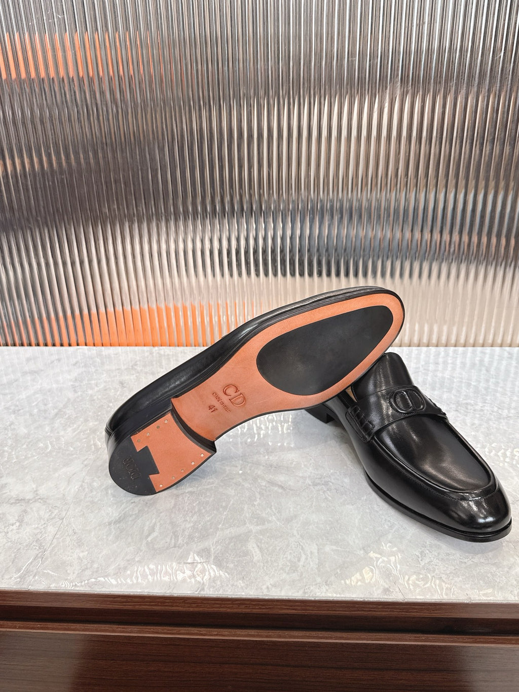 Black leather unisex loafer sole with orange underside and tread.