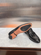 Black leather unisex loafer sole with orange underside and tread.