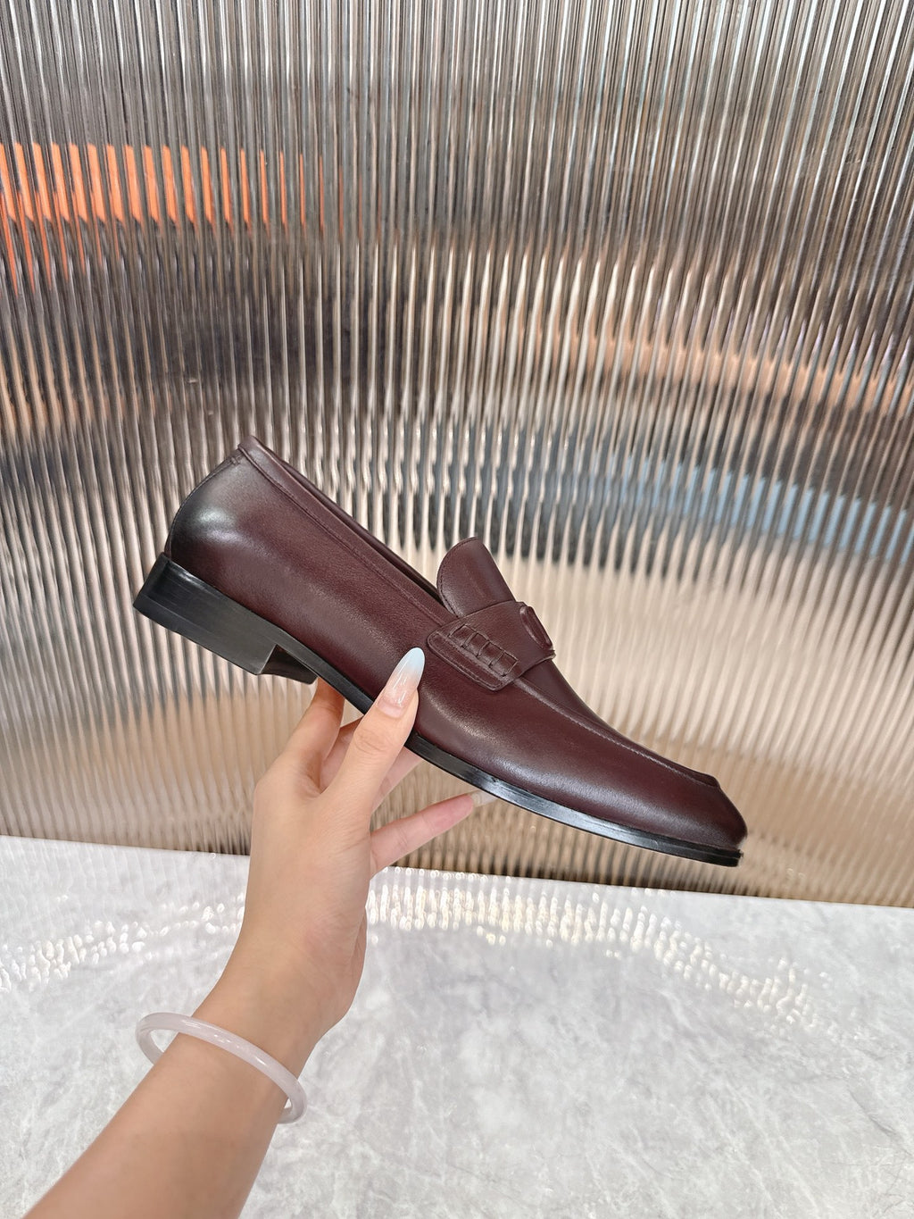 Burgundy leather loafer on display, DD strap detail and low sole