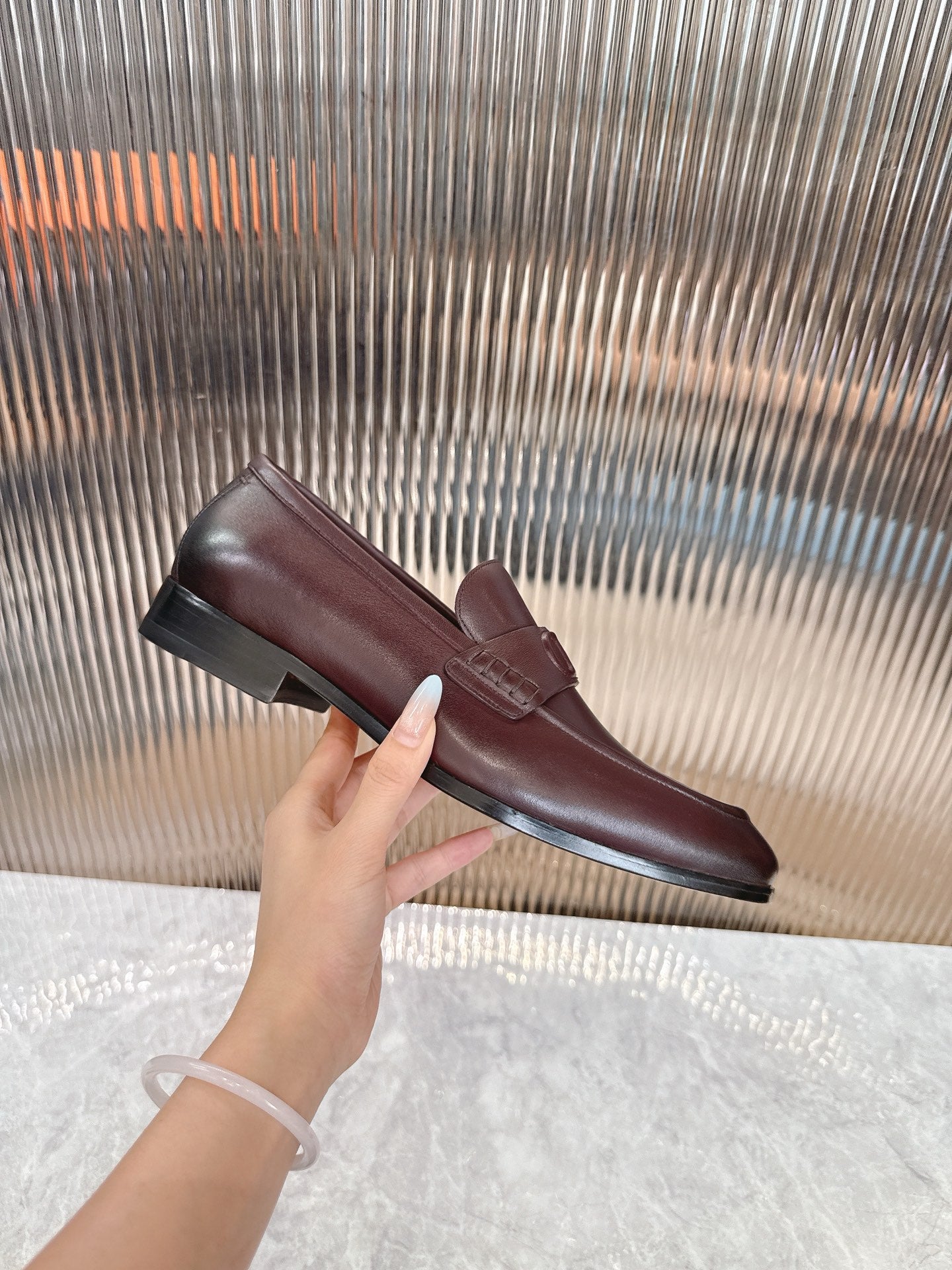 Burgundy leather loafer on display, DD strap detail and low sole