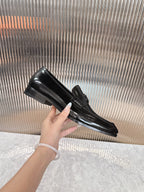 Single Dior black leather loafer held in hand, glossy finish and buckle