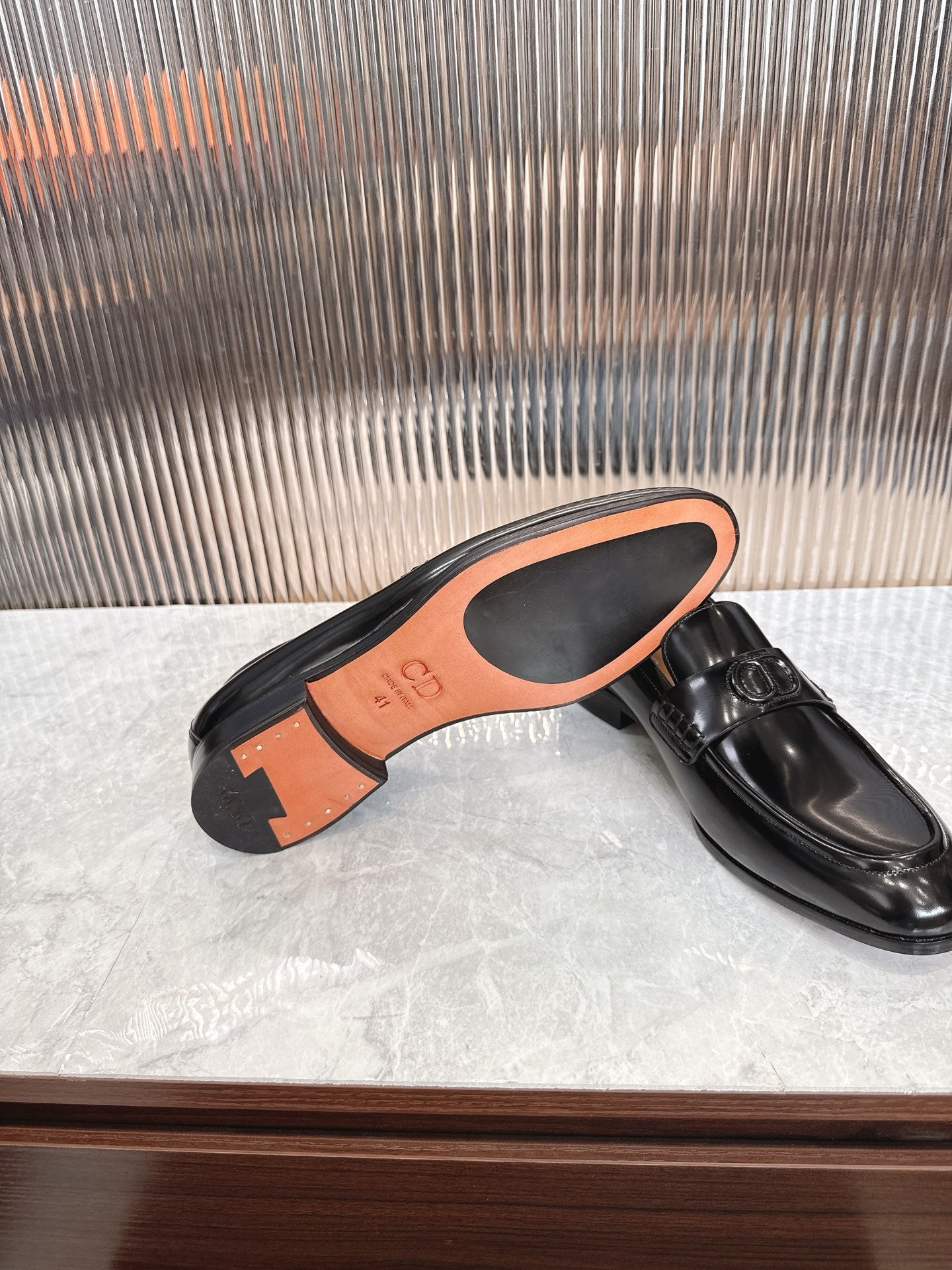 Dior unisex black leather loafer showing outsole with orange trim and buckle