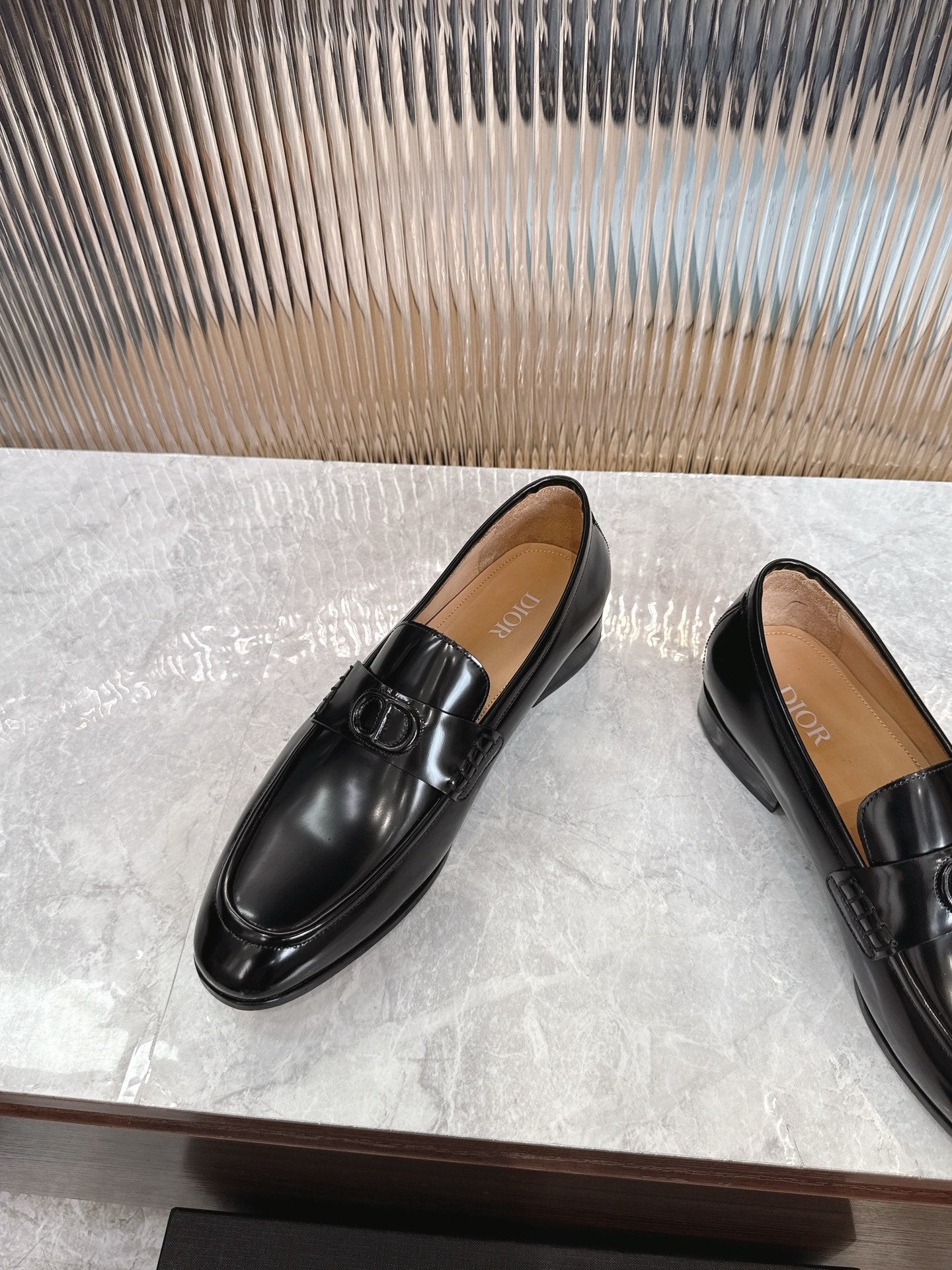 Dior unisex black leather loafers, angled view with smooth toe and buckle