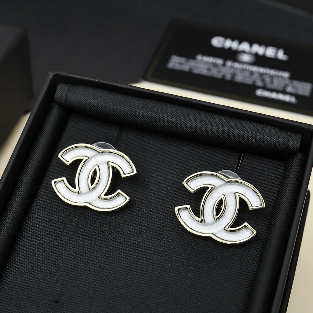 Chanel CC logo stud earrings, silver-tone with white enamel, on black fabric pad