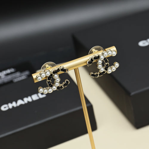 Gold-tone hoop earrings with pearl clusters and chain-link detailing, shown on stand