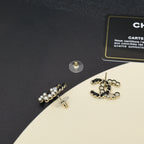 Gold-tone pearl earrings with chain links and circular cluster, laid on black cloth
