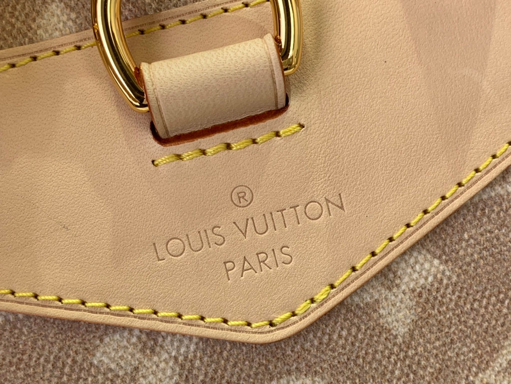 Louis Vuitton embossed label on tan leather edge with yellow stitching and gold hardware