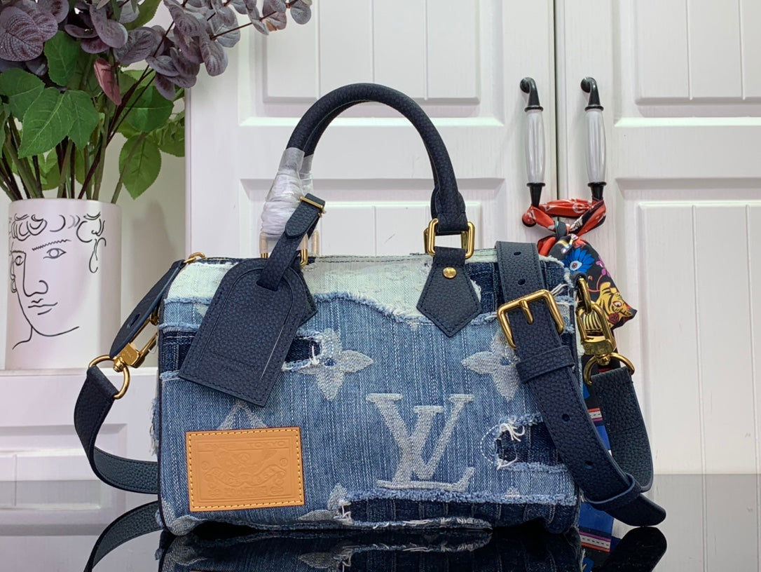 Blue denim patchwork handbag with top handle, shoulder strap, and gold-tone hardware.