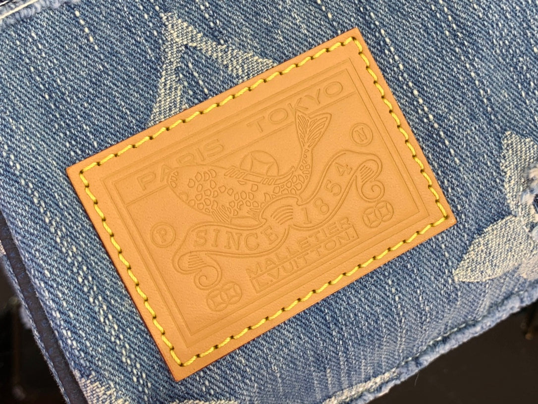 Tan leather patch with embossed logo and yellow stitched border on denim.