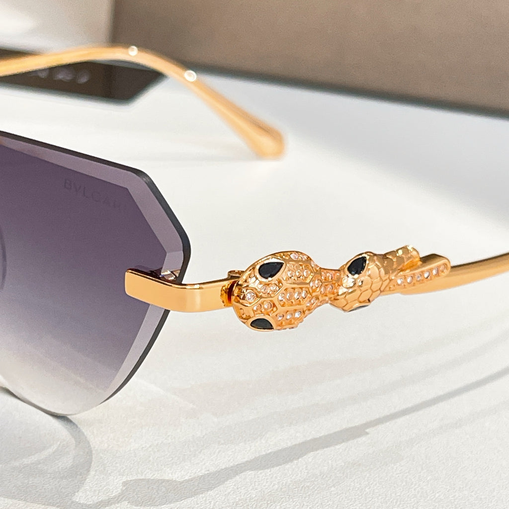 Gold-tone sunglasses with jewel-like oval charm on the temple and dark tinted lenses