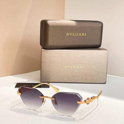 Gold-tone cat-eye sunglasses with dark purple gradient lenses and decorative hinge detail
