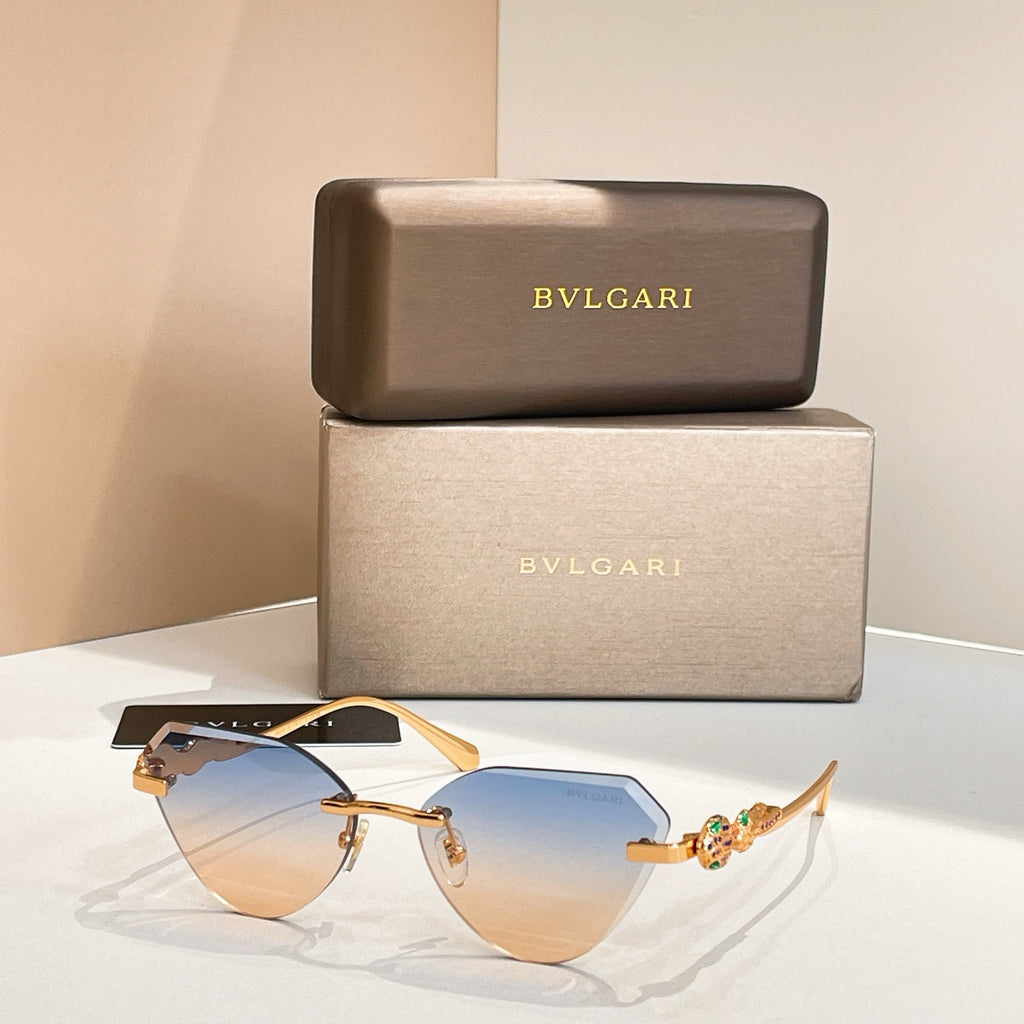Gold-tone cat-eye sunglasses with blue gradient lenses and decorative hinge detail