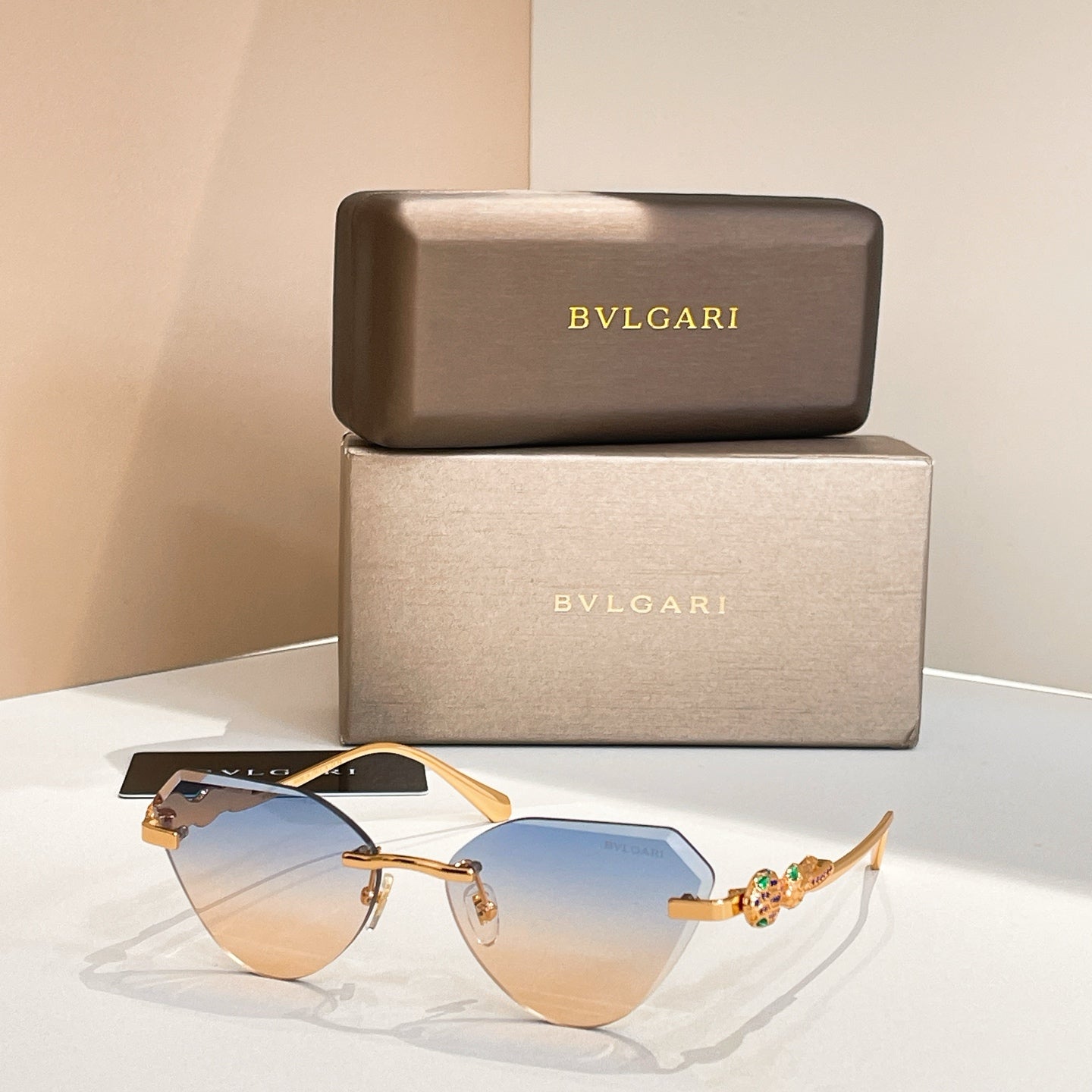Gold-tone cat-eye sunglasses with blue gradient lenses and decorative hinge detail