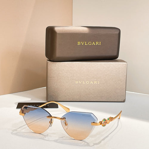 Gold-tone cat-eye sunglasses with blue gradient lenses and decorative hinge detail