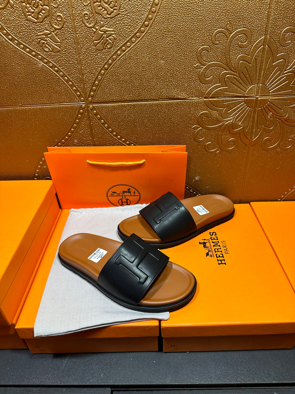 Black leather slide sandals with embossed H strap, flat sole