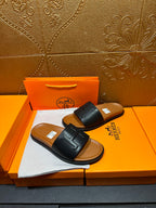 Black leather slide sandals with embossed H strap, flat sole