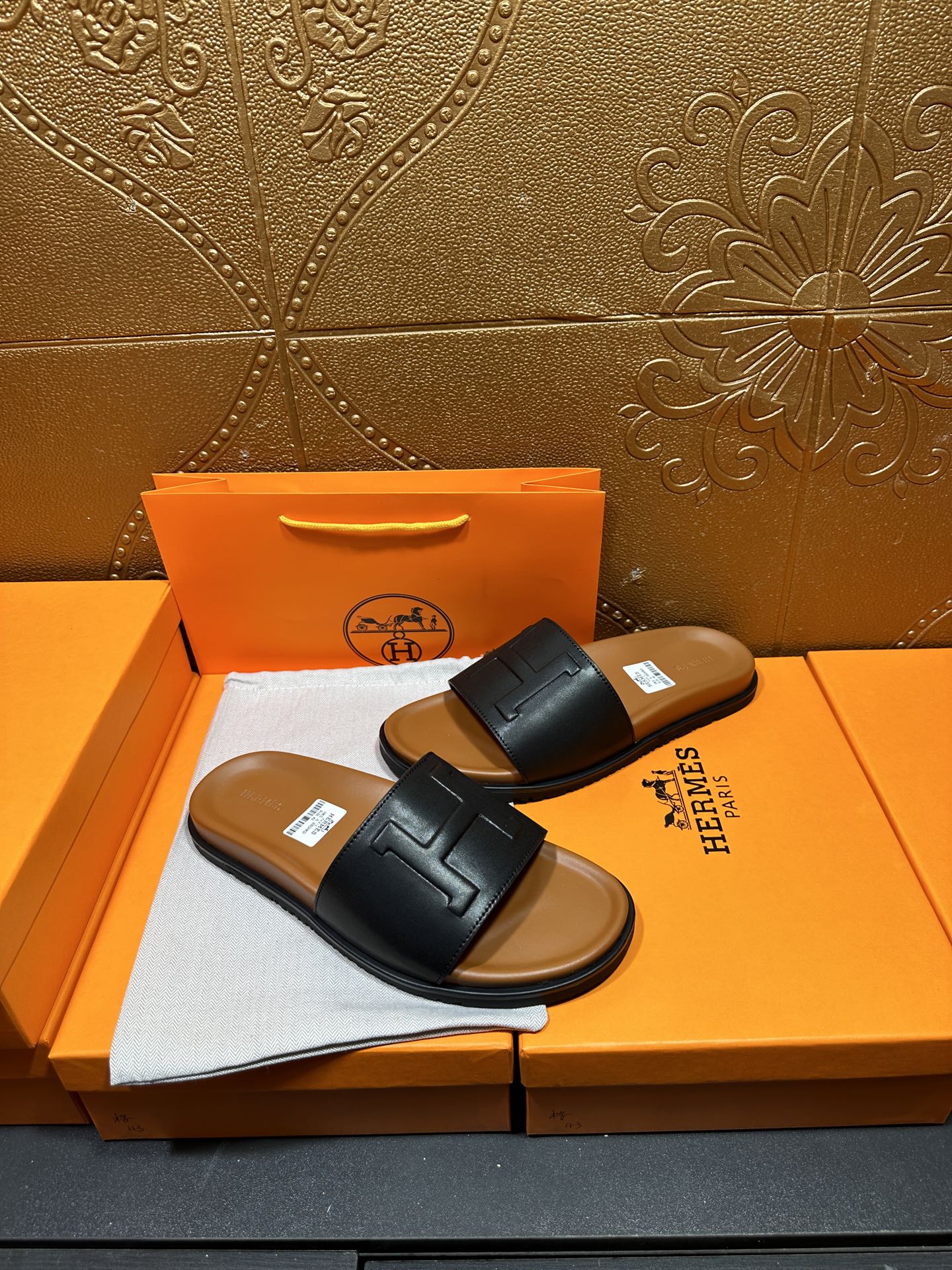 Black leather slide sandals with embossed H strap, flat sole