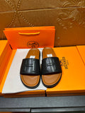 Black leather slide sandals with embossed H logo strap