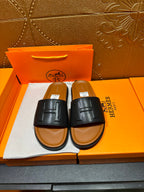 Black leather slide sandals with embossed H logo strap