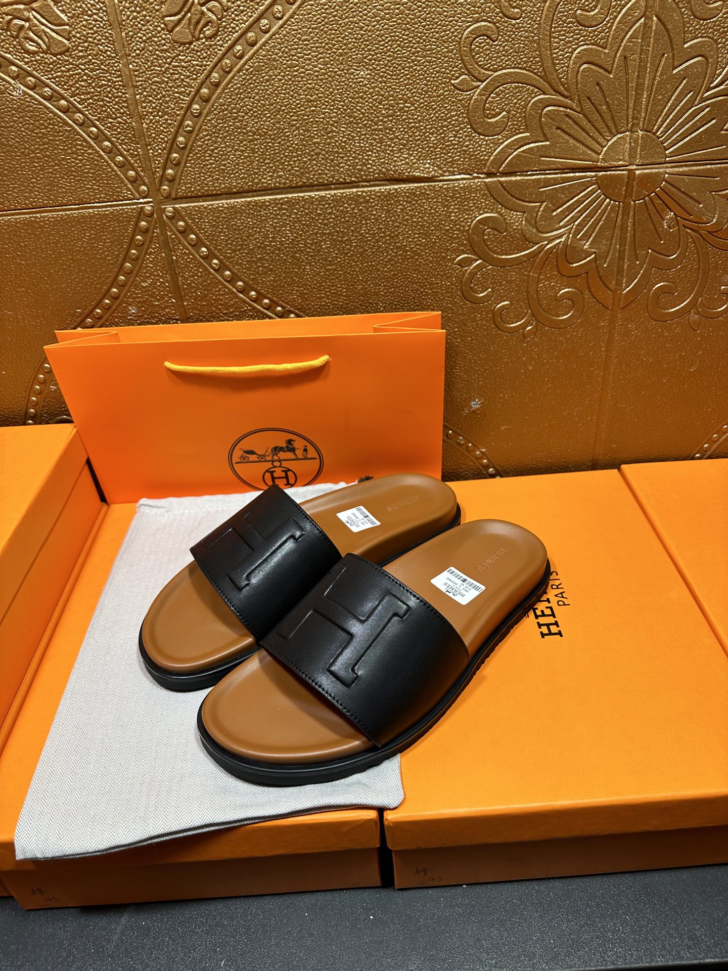 Black leather slide sandals with embossed H logo straps
