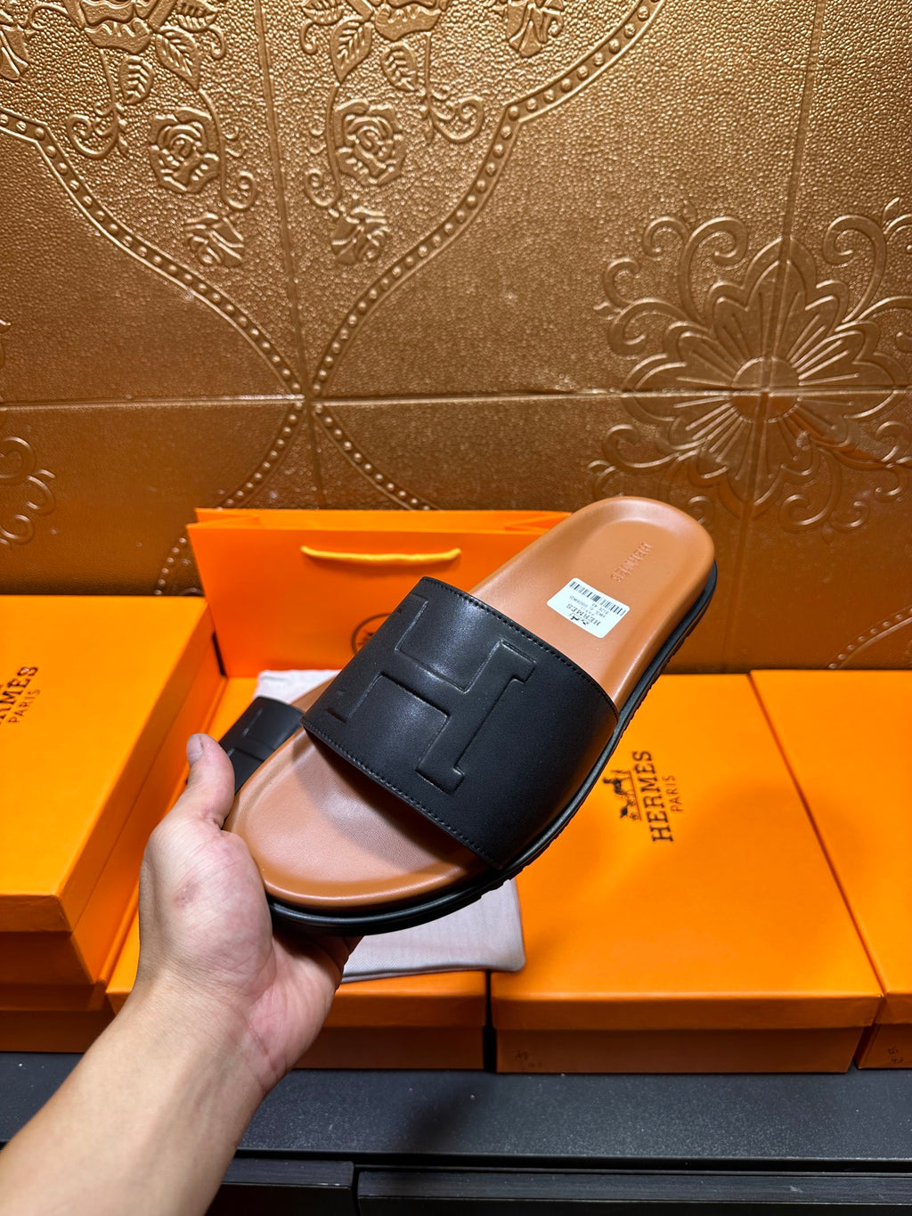Side view black leather slide sandal with embossed H strap, tan footbed